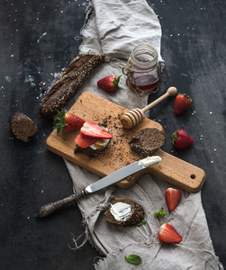 Breakfast set  Black baguette toasts with fresh strawberries  honey and mascarpone cheese on dark grunge table surface