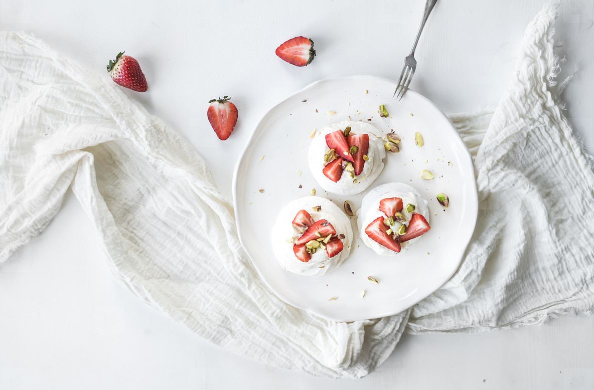 Small strawberry and pistachio pavlova meringue cakes with mascarpone cream