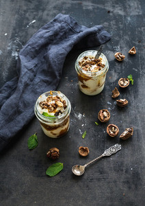 Walnut and salted caramel ice cream in glass jars with fresh mint over dark grunge surface