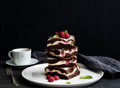 Brownies cheesecake tower with raspberries on white ceramic plate