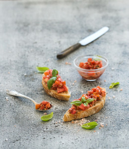 Tomato and basil bruschetta sandwich over grunge gray background