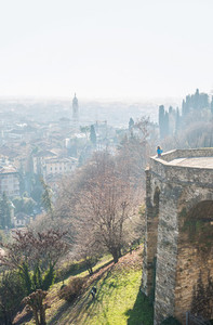 Woman standing at Venetian wall edge and watching the view of ancient italian town Bergamo
