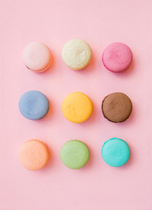 Sweet colorful French macaroon biscuits on pastel pink background