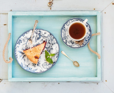 Piece of double crust plum pie and black tea in vintage porcelain cup  blue wooden tray  Top view  horizontal