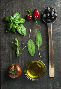 Vegetables and herbs on dark rustic wooden background  Greek black olives  fresh green sage  rosemary  basil herbs  oil  tomato