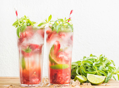 Strawberry mojito summer cocktails with mint and lime in tall glasses