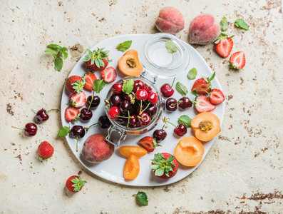 Healthy summer fruit variety  Sweet cherries  strawberries  blackberries  peaches  bananas and mint leaves on blue backdrop
