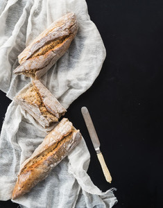 French baguette broken into pieces on a white kitchen towel with