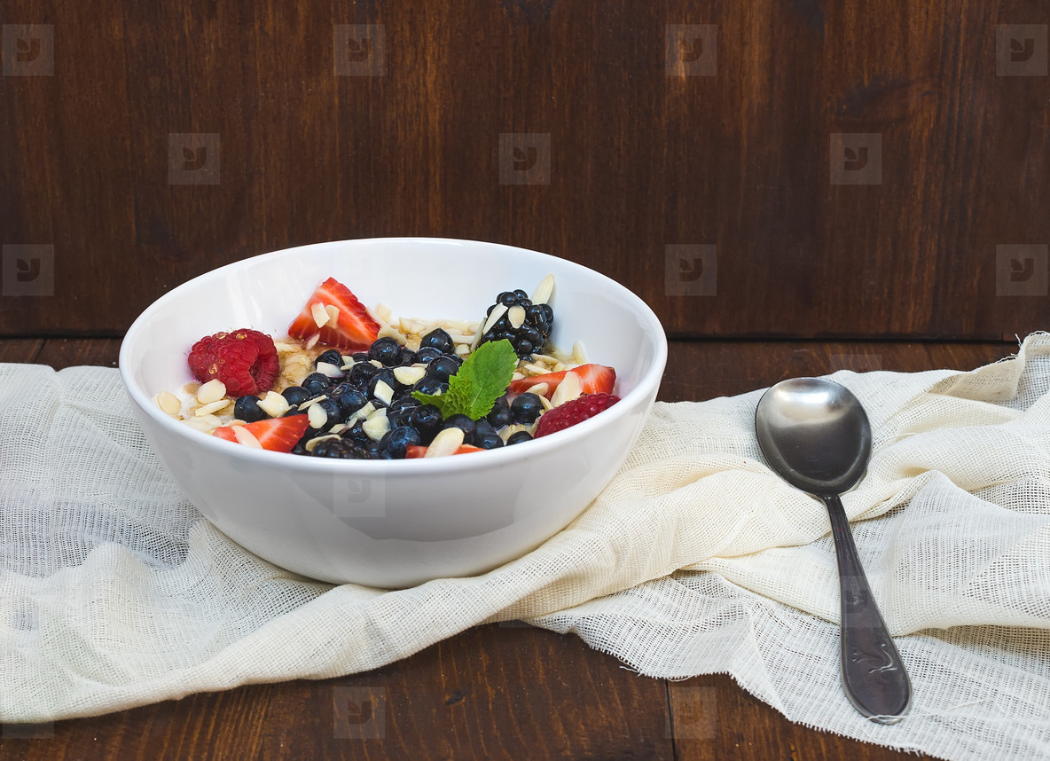 A bawl of oat porridge with fresh berries, honey, almond petals 