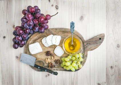 Goat brie cheese with fresh grapes and honey on a rustic wooden