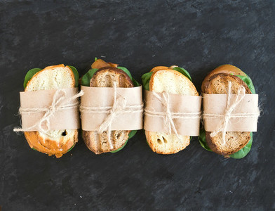 Chicken and spinach sandwiches wrapped in craft paper over a dar