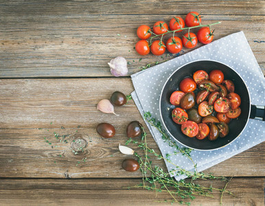 Roasted cherry tomatoes with garlic and thyme in a cooking pan o