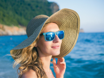 A girl in sunglasses and a hat on the beach
