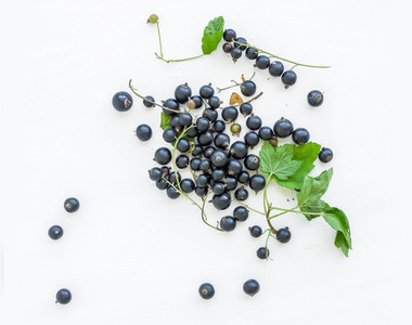 Black currant berries and green leaves over a white wooden sufra