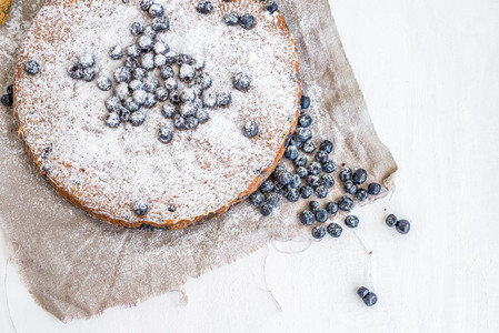 Blueberry cake with fresh blueberries and sugar powder on a beig
