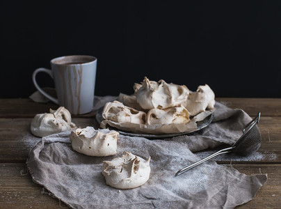 White meringue and mug of hot chocolate on a rustic wooden table Black backdro