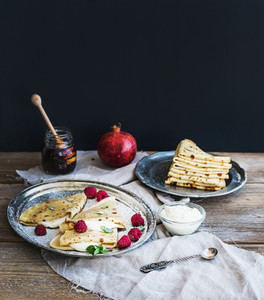 Thin pancakes or crepes with fresh raspberry  cream  mint  on a rustic wooden desk
