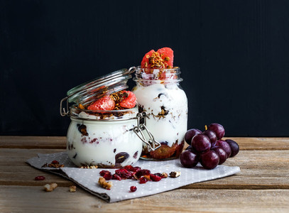 Yogurt and oat granola with grapes pomegranate grapefruit in tall glass jar