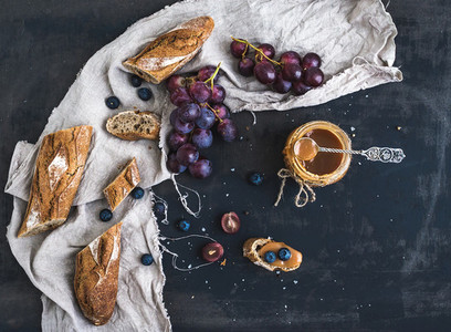 French baguette cut into pieces red grapes blueberry and salt caramel sauce on rustic dark background