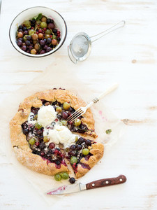 Summer crostata or galette pie with fresh garden berries and vanilla ice cream over white wooden background top view