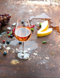 Glass of rose wine with berries  melon  grapes and ice on grunge rusty metal background