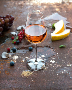 Glass of rose wine with berries  melon  grapes and ice on grunge rusty metal background