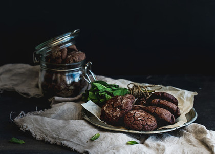 Dark chocolate chip cookies with fresh mint on dark backdrop