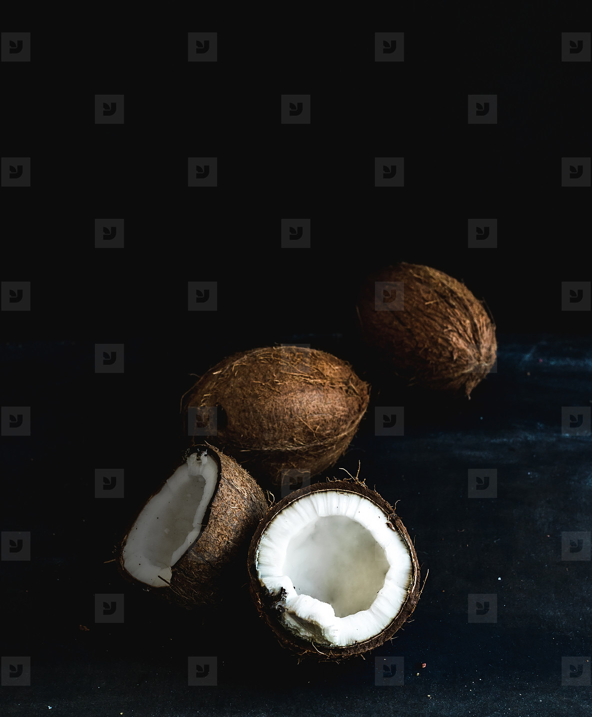 Whole and broken coconuts over dark grunge background