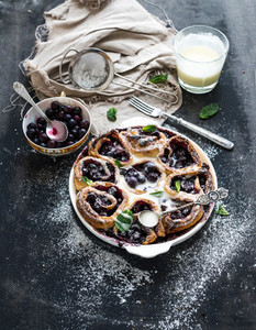 Blueberry buns with fresh mint and creamy sauce on dark backdrop