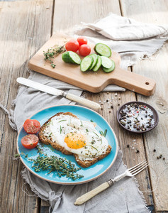 Breakfast set Whole grain andwich with fried egg vegetables and herbs on rustic wooden table morning mood