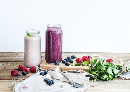Fresh healthy smoothie with blueberries raspberries in glass jars and mint