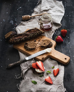 Breakfast set  Black baguette toasts with fresh strawberries  honey and mascarpone cheese on dark grunge table surface