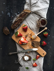 Breakfast set Black baguette toasts with fresh strawberries honey and mascarpone cheese on dark grunge table surface