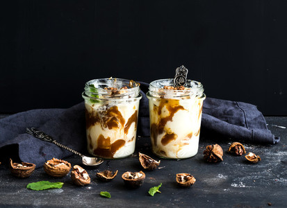 Walnut and salted caramel ice cream in glass jars with fresh mint over dark grunge backdrop