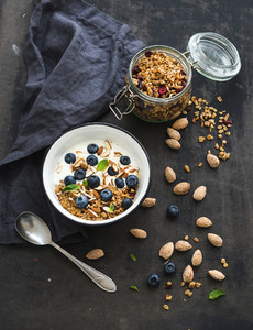 Healthy breakfast Oat granola with fresh blueberries almond yogurt and mint in a rustic metal bowl