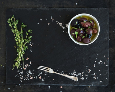 Food frame on dark stone backdrop Mediterranean olives in oil fresh thyme spices