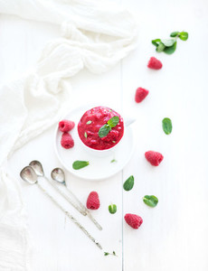 Raspberry sorbet ice cream with mint leaves  and spoons on white background