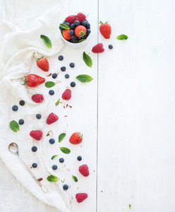 Berry frame with copy space on right  Strawberries  raspberries  blueberries and mint leaves  white wooden background