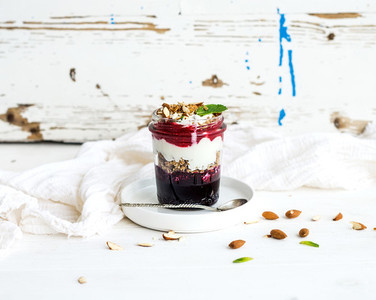 Yogurt oat granola with berries honey and nuts in glass jar rustic white  background