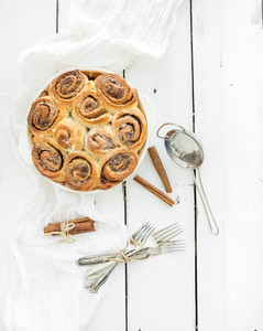 Freshly baked cinnamon buns in dish on a rustic wooden table  top view