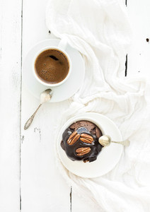Tasty homemade brown muffin with chocolate ganache icing and pecan nuts  cup of black coffee