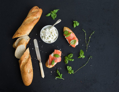 Salmon ricotta and basil sandwiches with baguette over black grunge background Top view