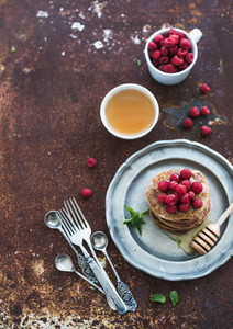 Breakfast set  Buckwheat pancakes with fresh raspberries  honey and mint leaves over grunge metal background