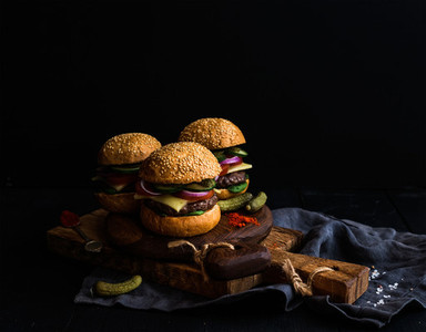 Fresh beef burgers with pickles and spices on rustic wooden boards  black background