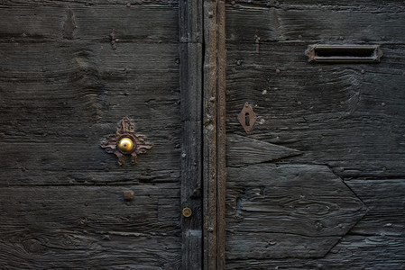 Old medieval italian wooden door with metal handle and a mail slot
