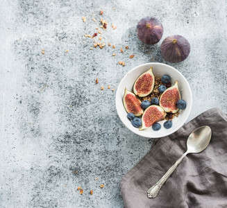 Healthy breakfast  Bowl of oat granola with yogurt  fresh blueberries and figs over grunge grey backdrop