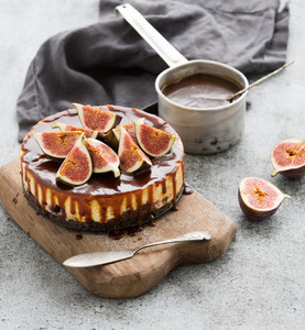 Cake with fresh figs and salted caramel on wooden serving board over grunge background