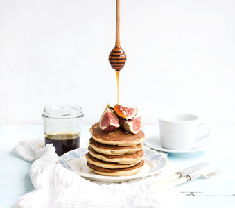 Pancake tower with fresh figs and honey on a rustic plate White background