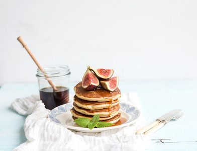 Pancake tower with fresh figs and honey on a rustic plate  White background