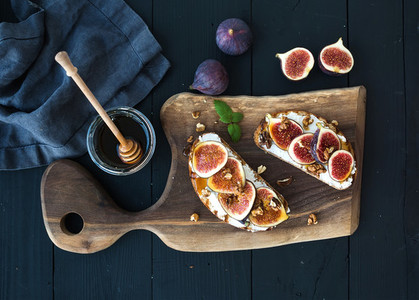 Sandwiches with ricotta  fresh figs  walnuts and honey on rustic wooden board